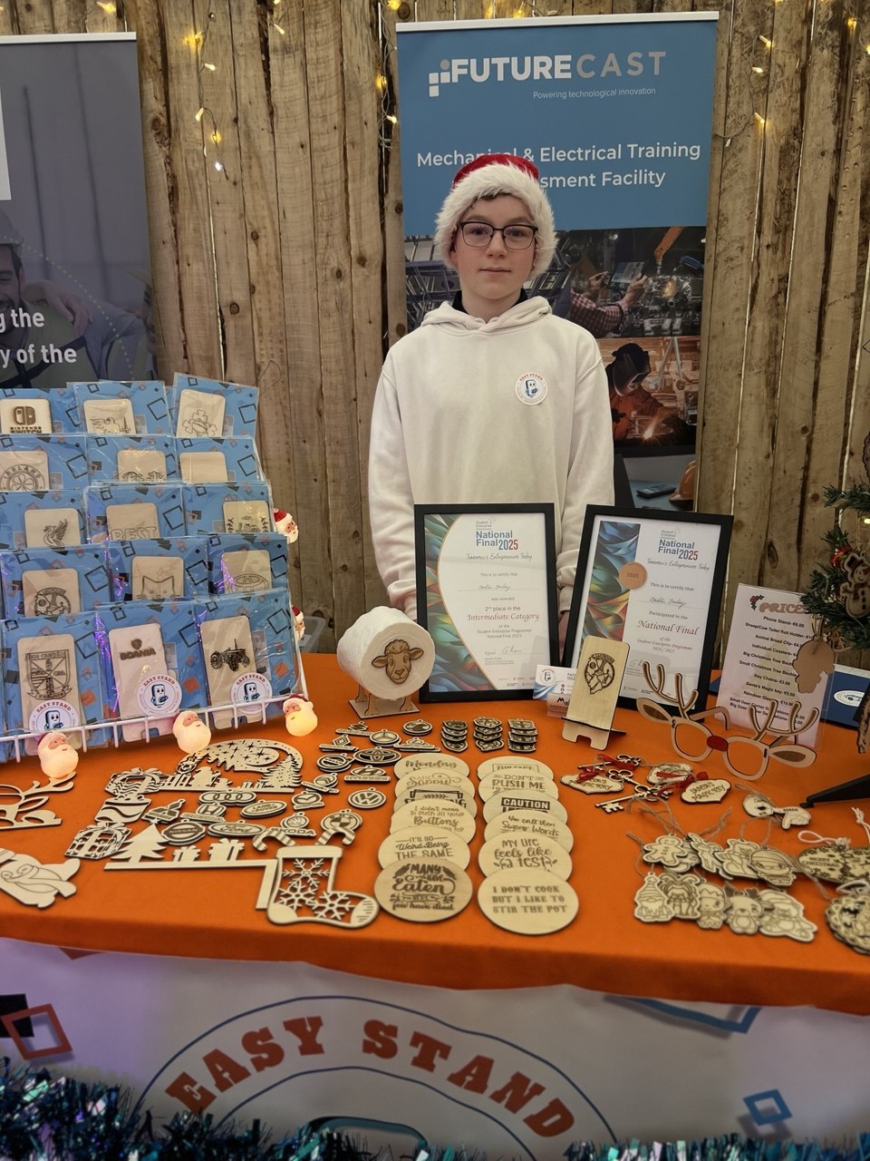 A boy with laser-cut wooden gifts and Student Enterprise certificates