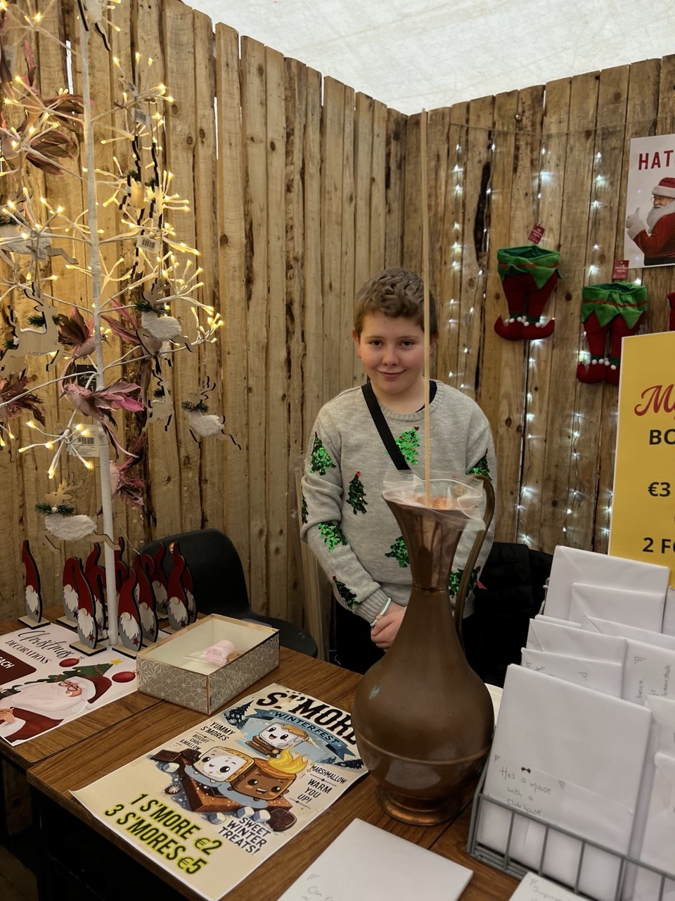 A boy at a s'mores stall with Christmas decorations