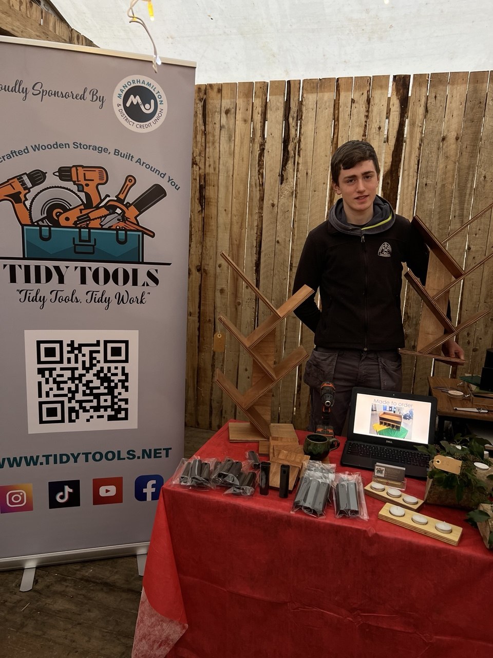 A teenager with handcrafted wooden storage and a Tidy Tools banner