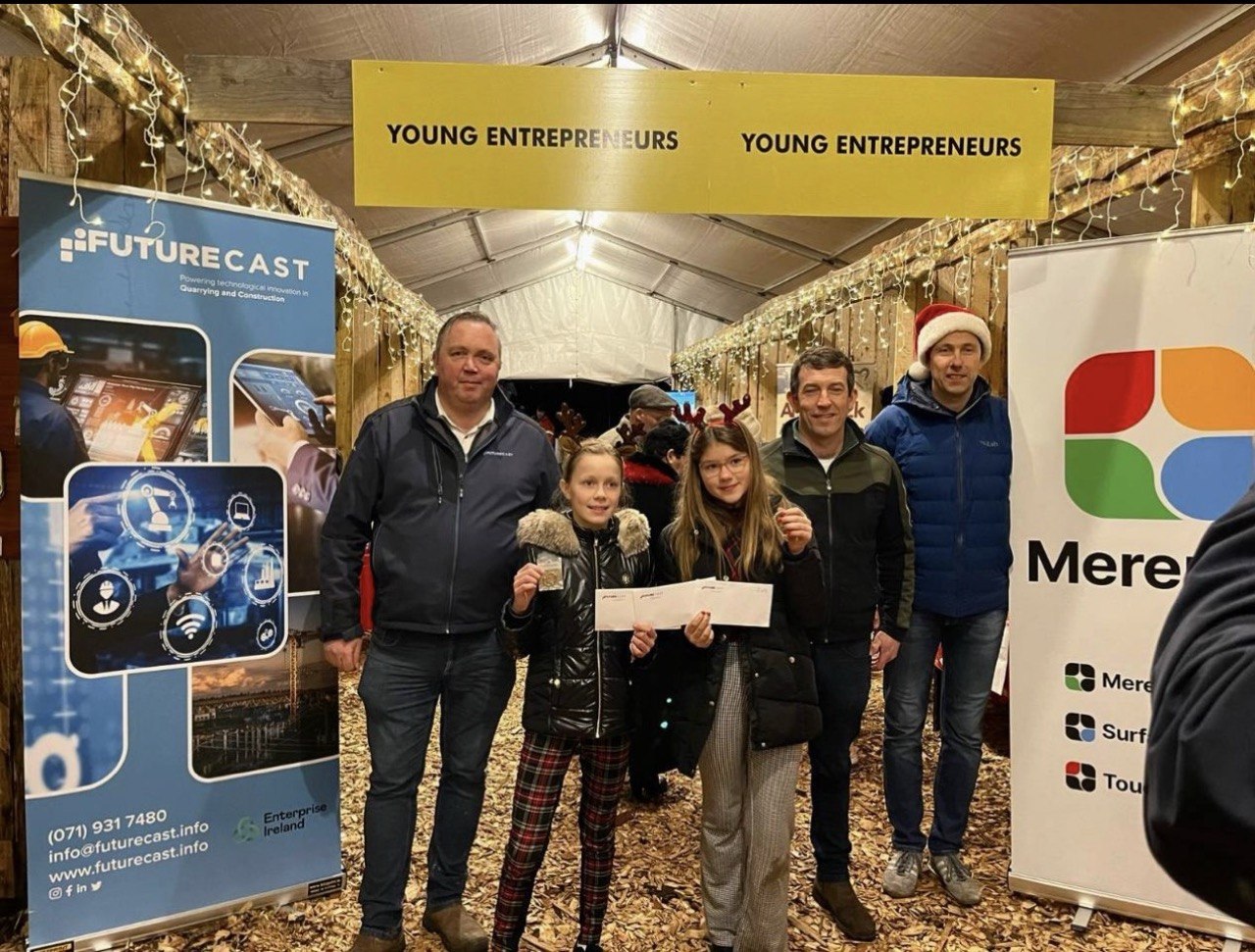 Two young entrepreneurs receive prizes from sponsors under the Young Entrepreneurs sign